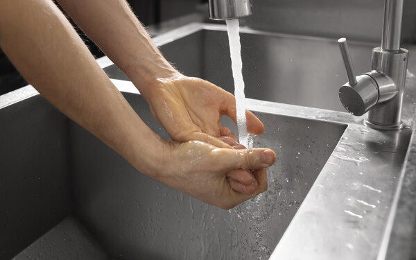 Personne se lavant les mains sous un robinet d'eau 